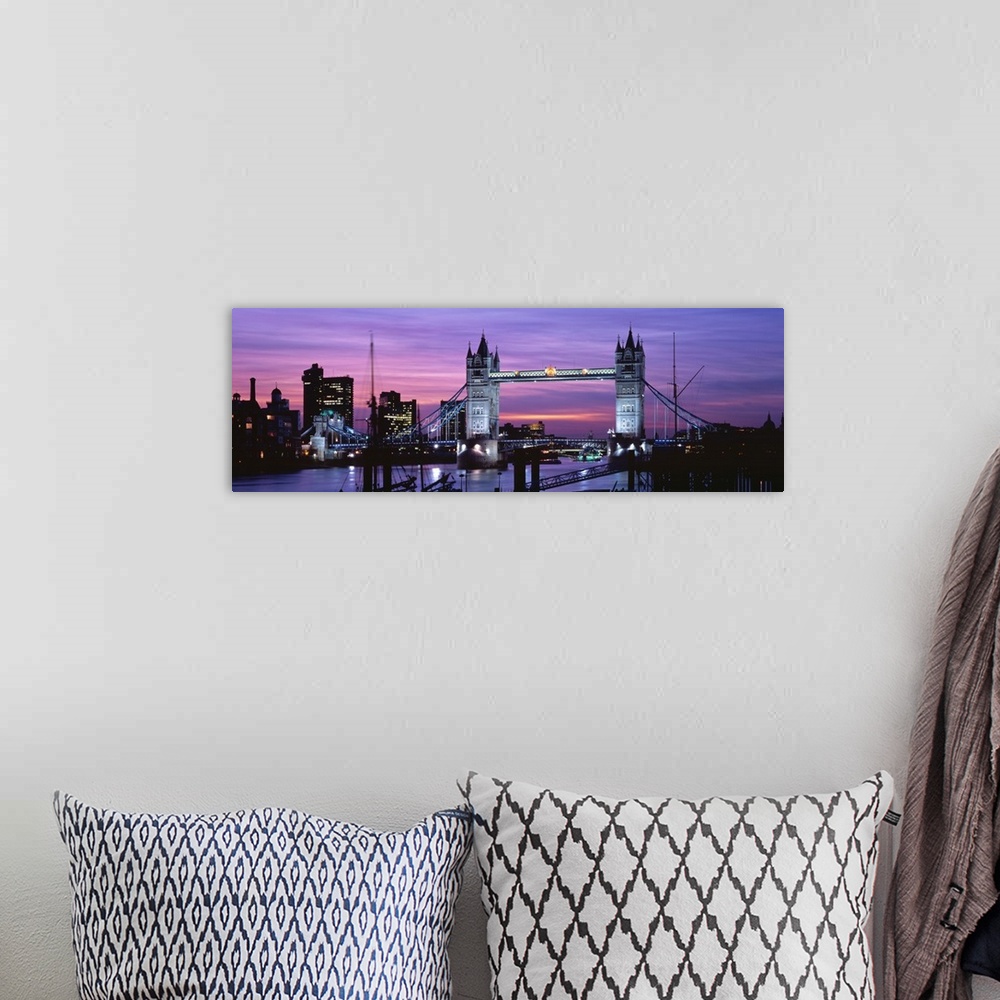 A bohemian room featuring Panoramic view of London's cityscape and the Tower Bridge in front of a pink and purple toned sun...