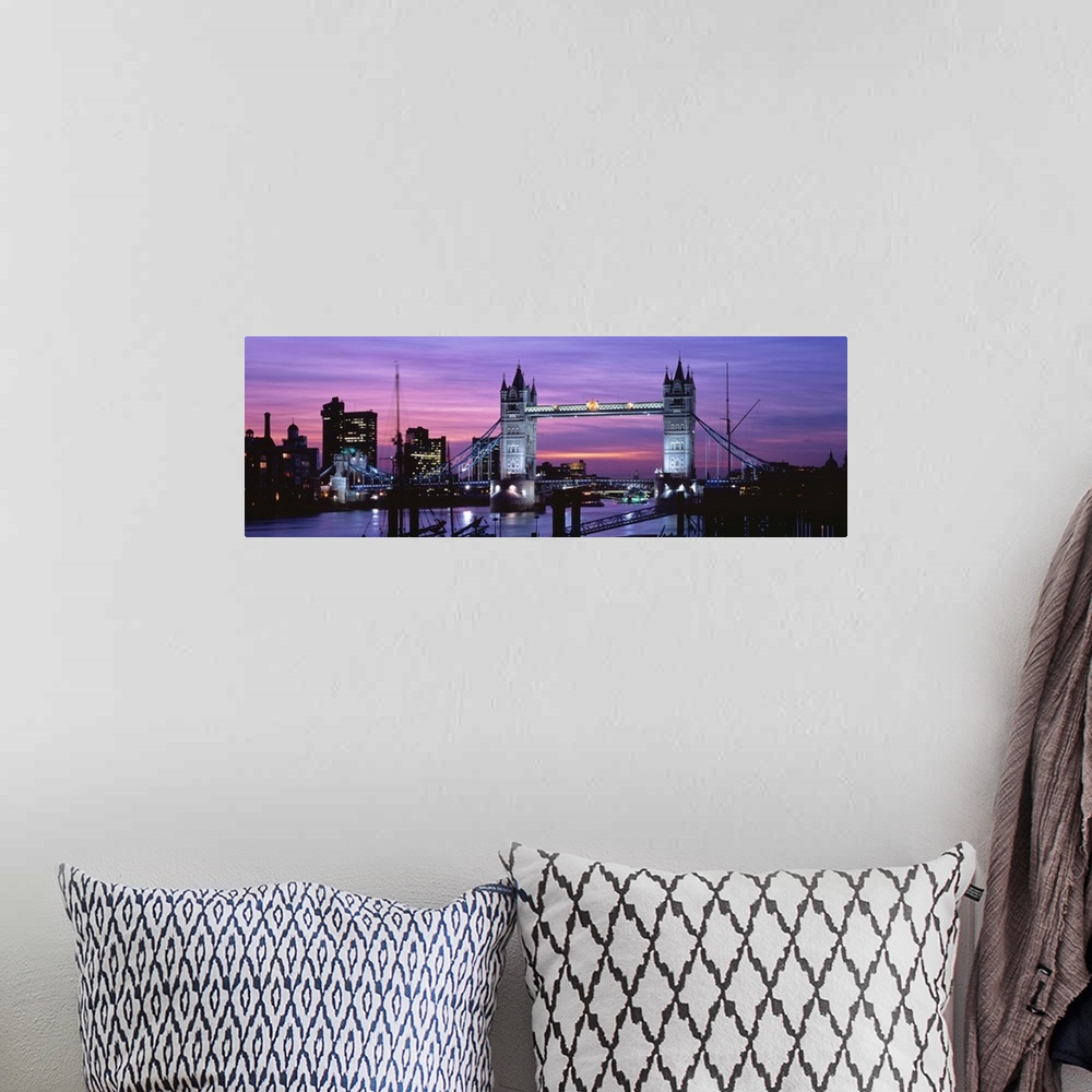 A bohemian room featuring Panoramic view of London's cityscape and the Tower Bridge in front of a pink and purple toned sun...