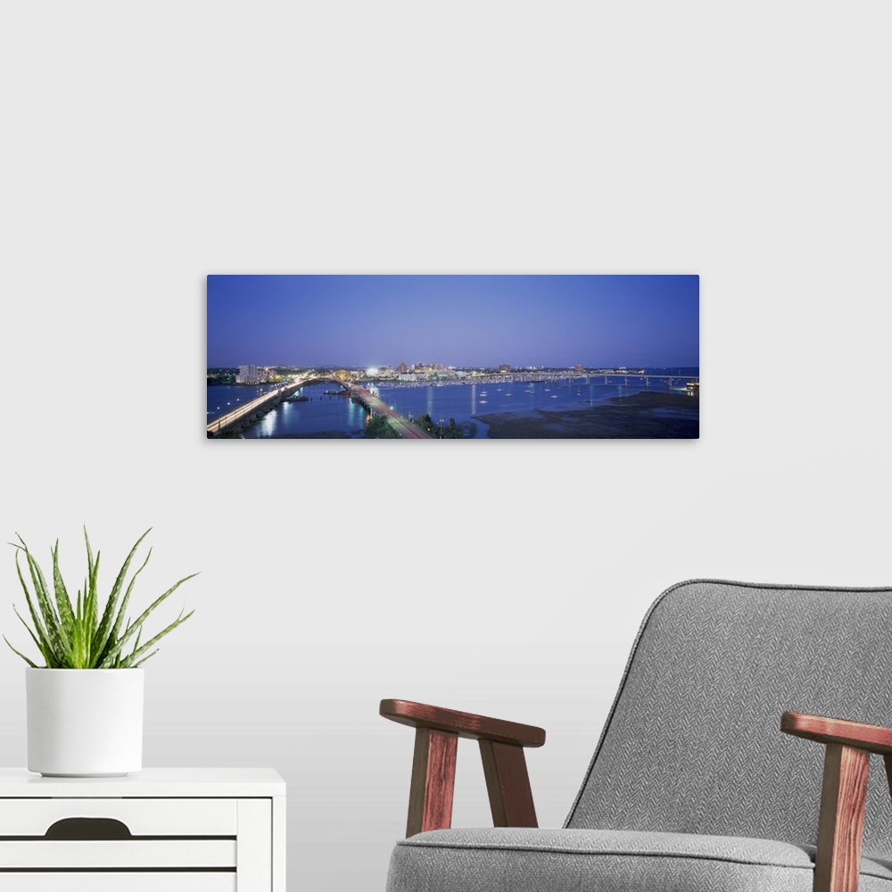 A modern room featuring Panoramic photograph on a big canvas of two bridges over water, leading toward the brightly lit C...