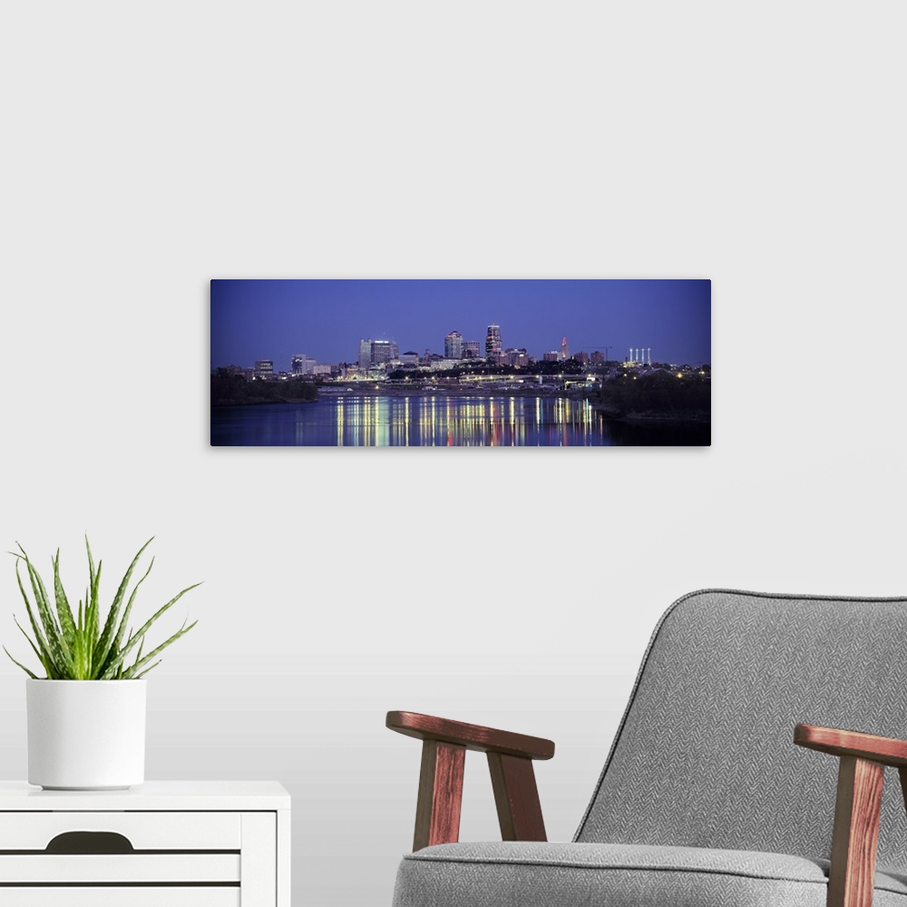 A modern room featuring Panoramic photograph of city skyline at dusk with the buildings lit up in the night sky.  The bri...