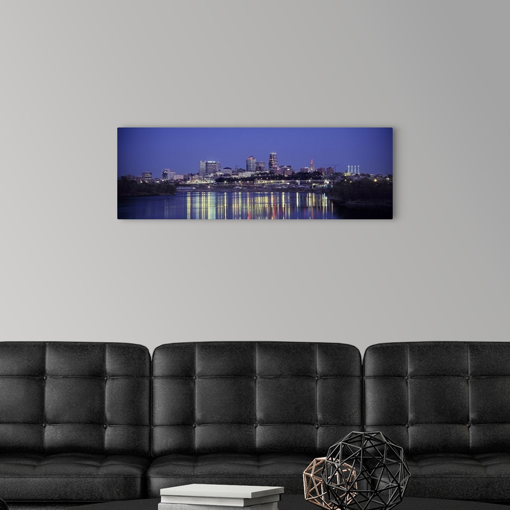 A modern room featuring Panoramic photograph of city skyline at dusk with the buildings lit up in the night sky.  The bri...