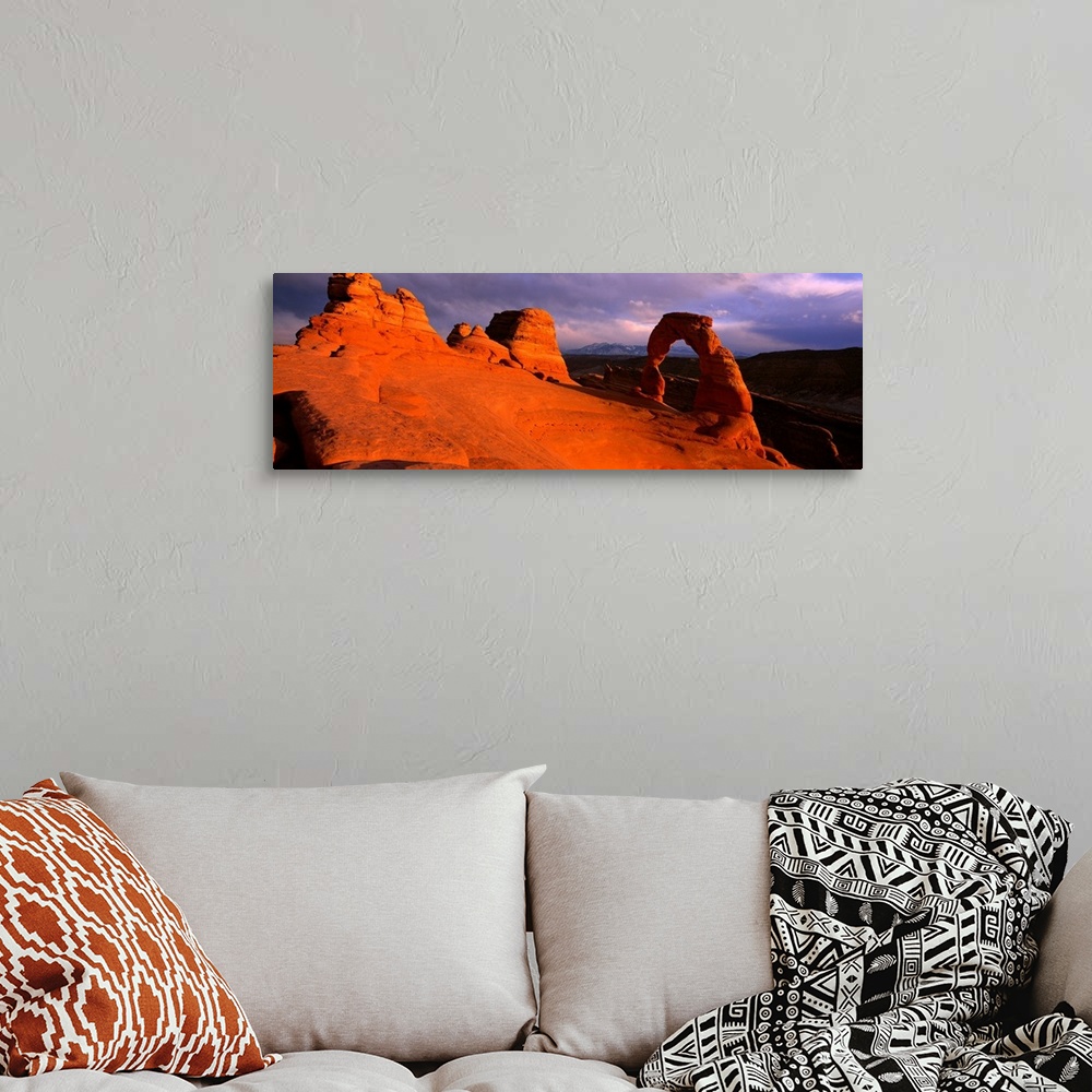 A bohemian room featuring A landscape photograph that is a panoramic shot of a wind eroded rock face illuminated a sunset.
