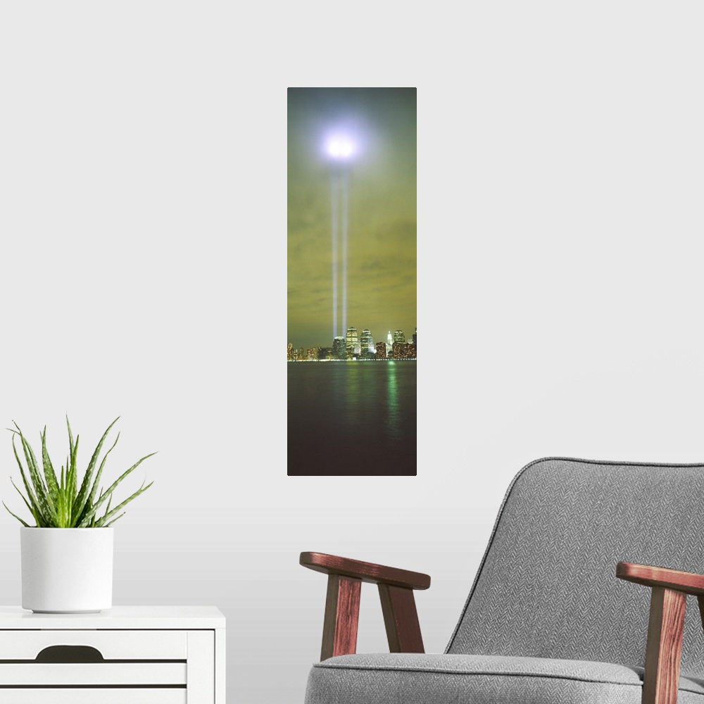 A modern room featuring Vertical panoramic piece of a photograph of the lights shining up from where the twin towers stood.