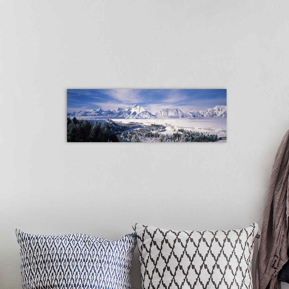 A bohemian room featuring Panoramic photograph of snow covered mountains with forest in the foreground under a cloudy sky .