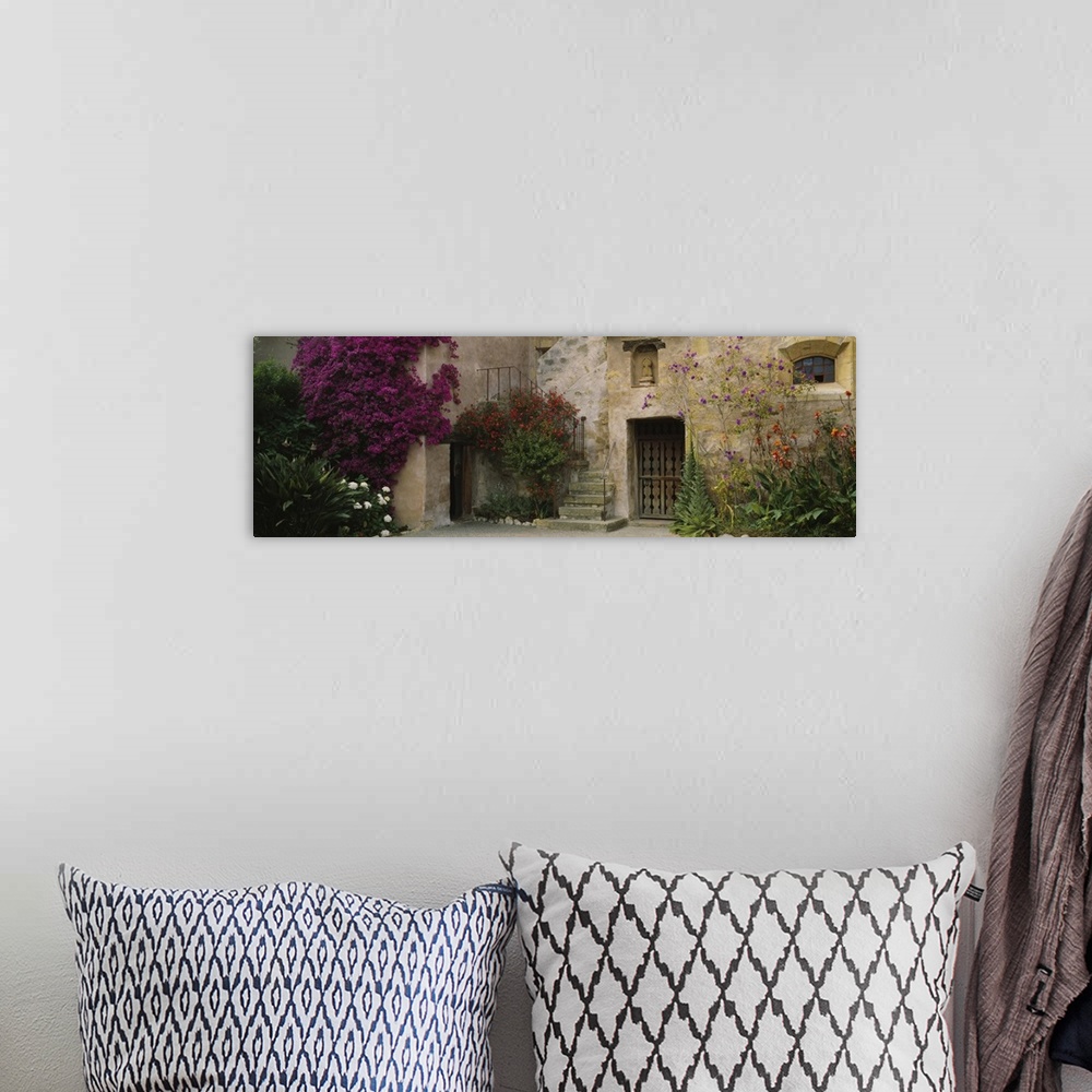 A bohemian room featuring Panoramic image of an Italian style stone house with large flowering bushes crawling up the side ...