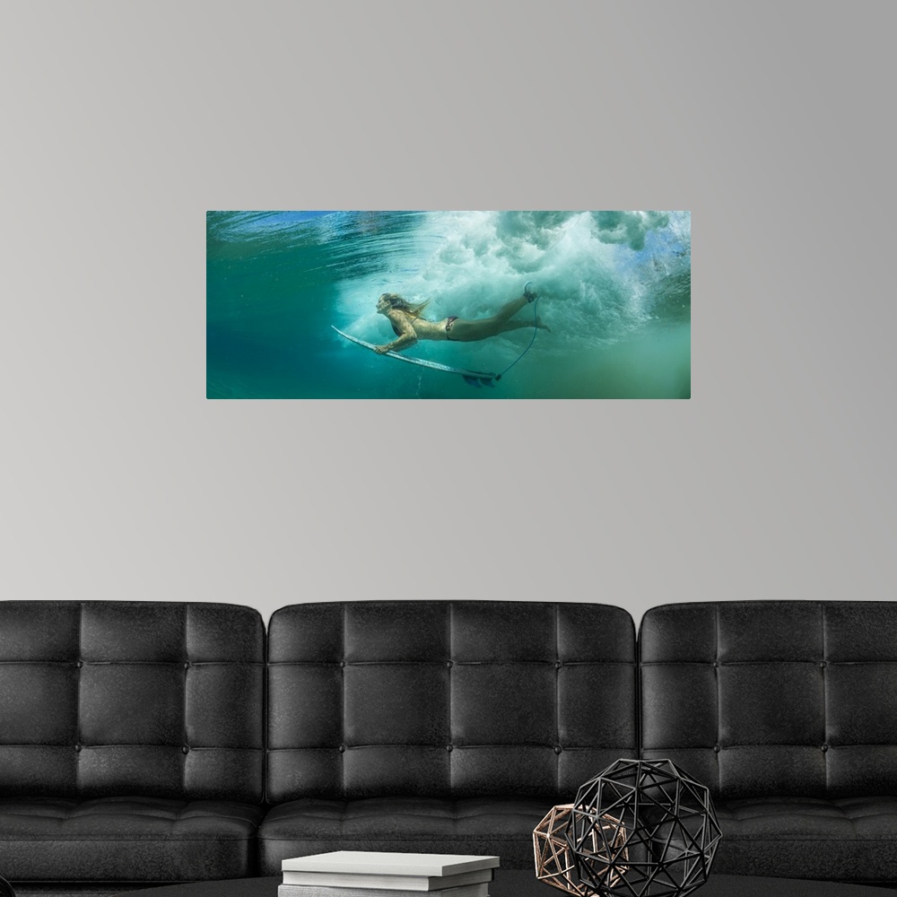 A modern room featuring Female surfer pushes under a wave while surfing, Clansthal, South Africa.