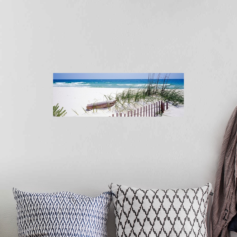 A bohemian room featuring Oversized landscape photograph of a fence running through grasses on the beach, in front of the r...
