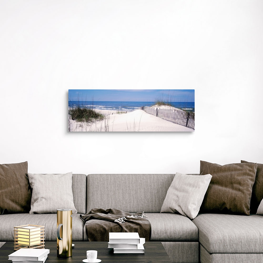 A traditional room featuring This panoramic photograph looks out to a calm sea over a dune covered in sea grass and a buried f...