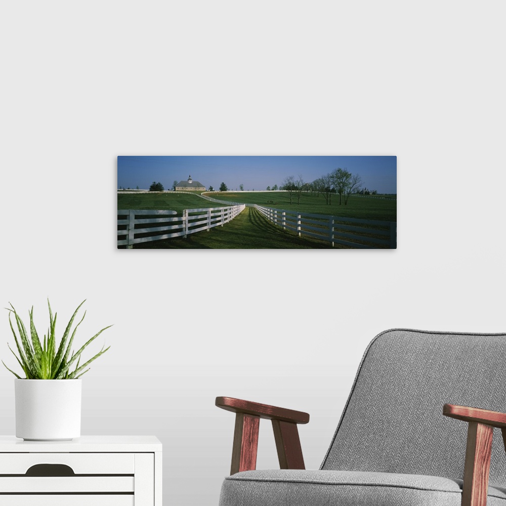 A modern room featuring Panoramic photograph of fenced pasture with house in the distance.