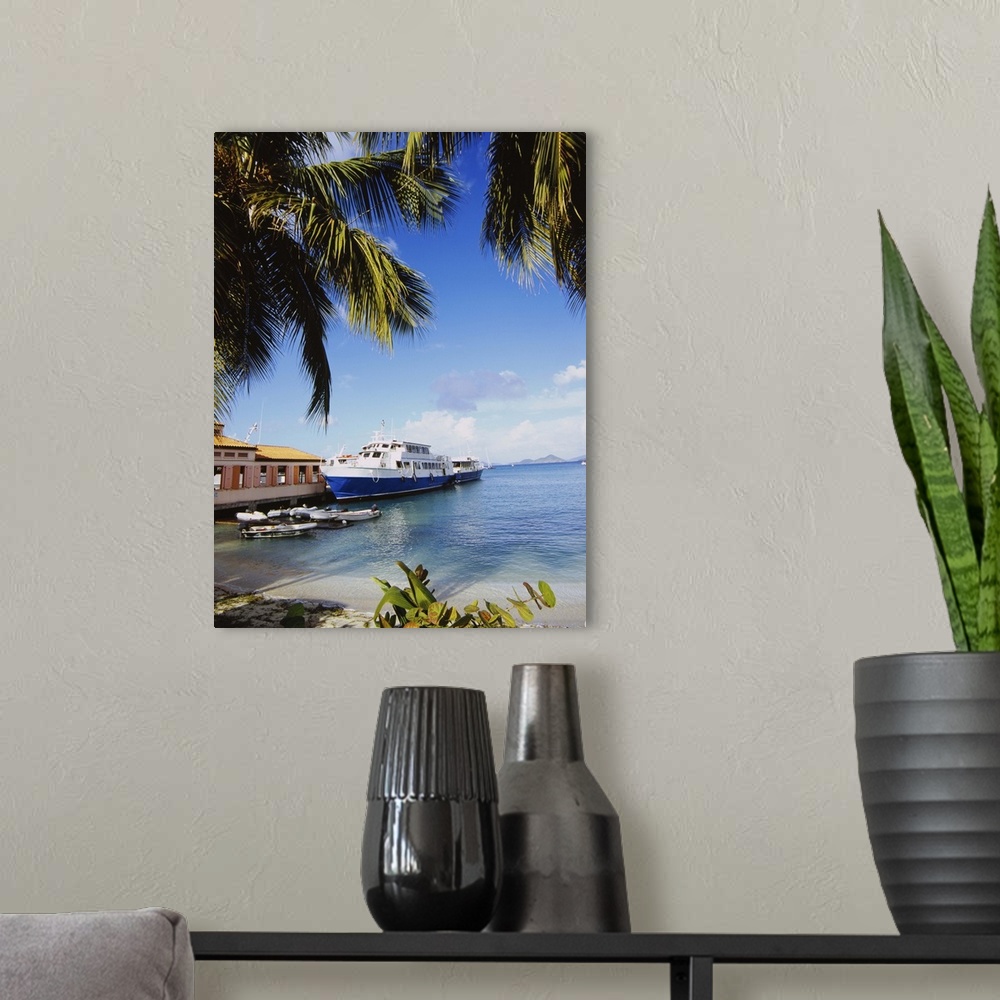 A modern room featuring A passenger boat is docked along a pier in the Caribbean. Palm trees on a beach hang over the top...