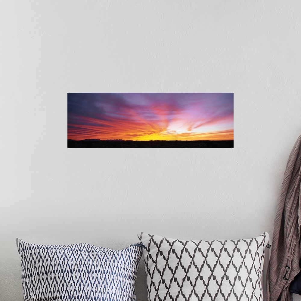 A bohemian room featuring The strip of land at the bottom of this piece is silhouetted by the beautiful sunset that has dip...