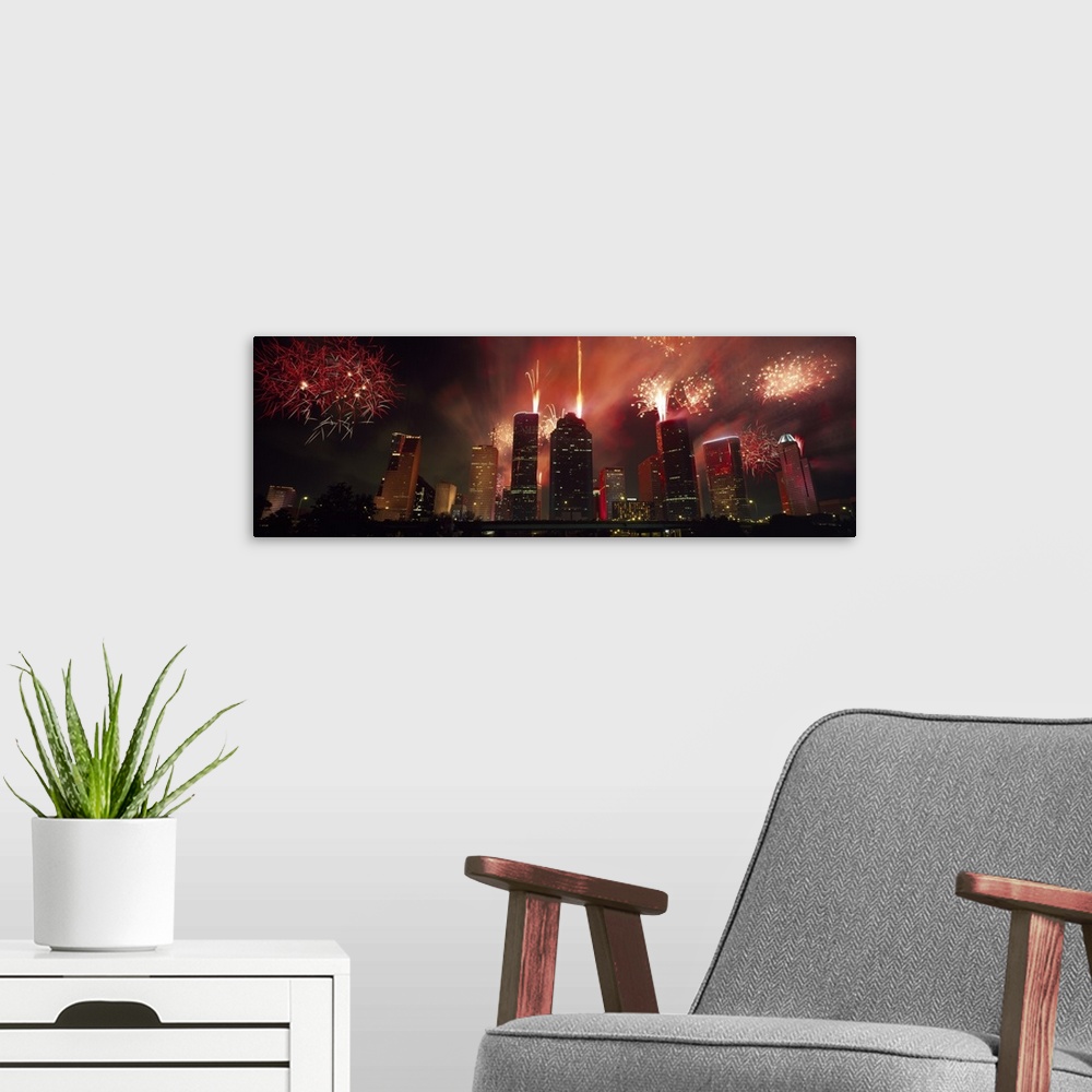 A modern room featuring Fireworks explode in the night sky behind the backdrop of the Houston downtown skyline.