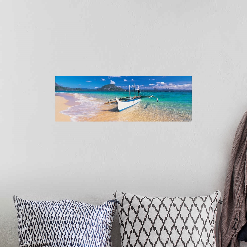 A bohemian room featuring A panoramic photograph of a tropical beach with mountains and island in the background with a boa...