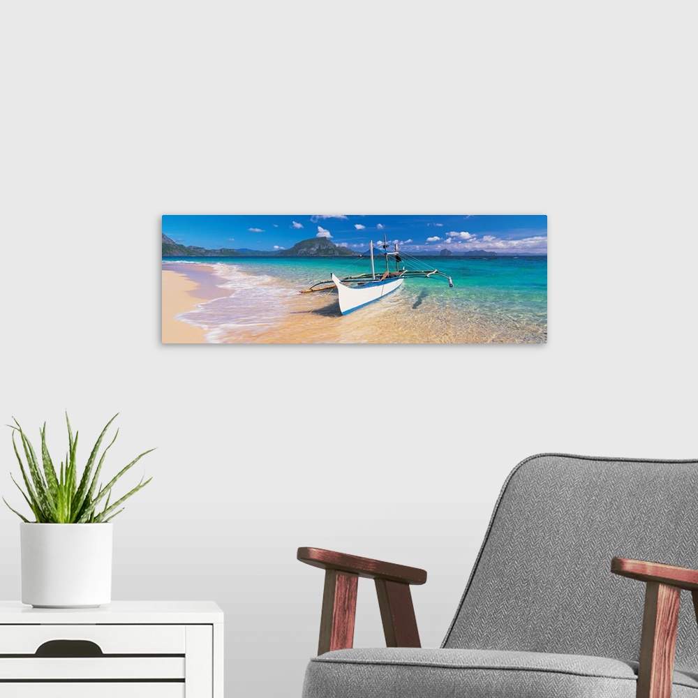 A modern room featuring A panoramic photograph of a tropical beach with mountains and island in the background with a boa...
