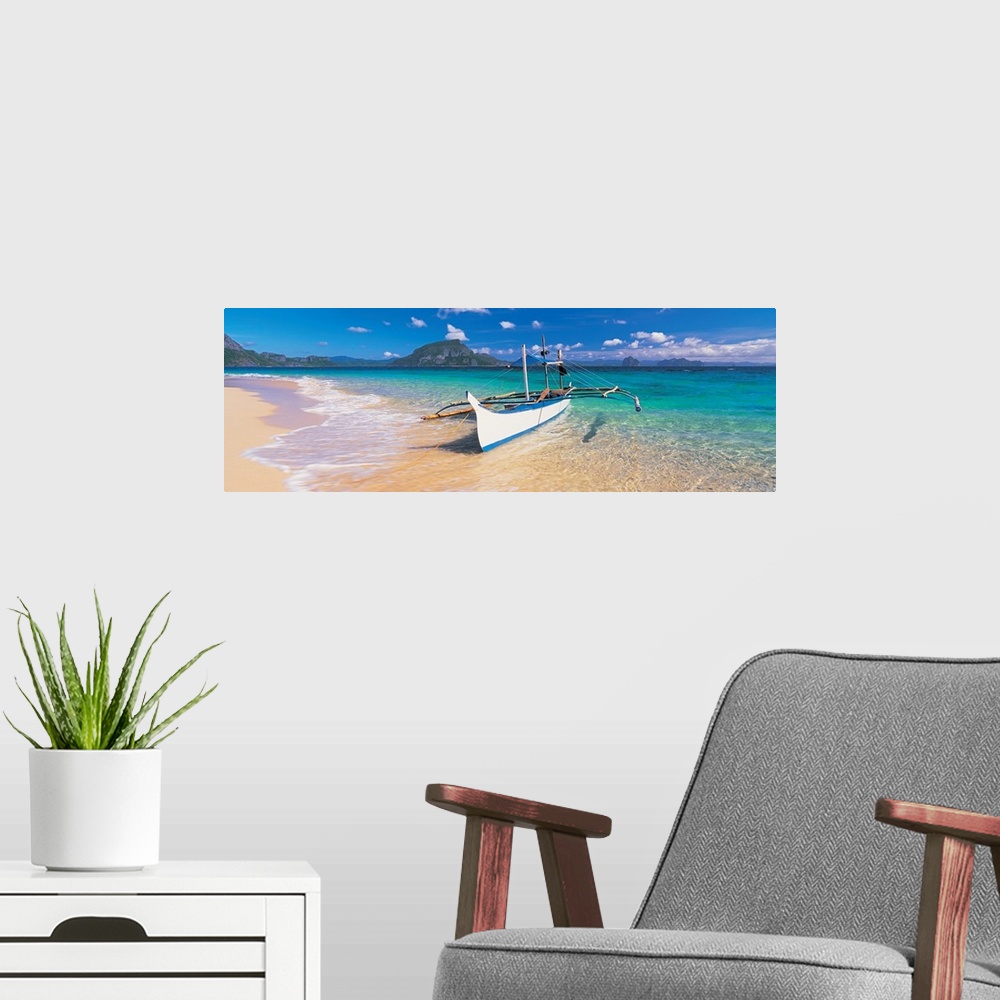 A modern room featuring A panoramic photograph of a tropical beach with mountains and island in the background with a boa...