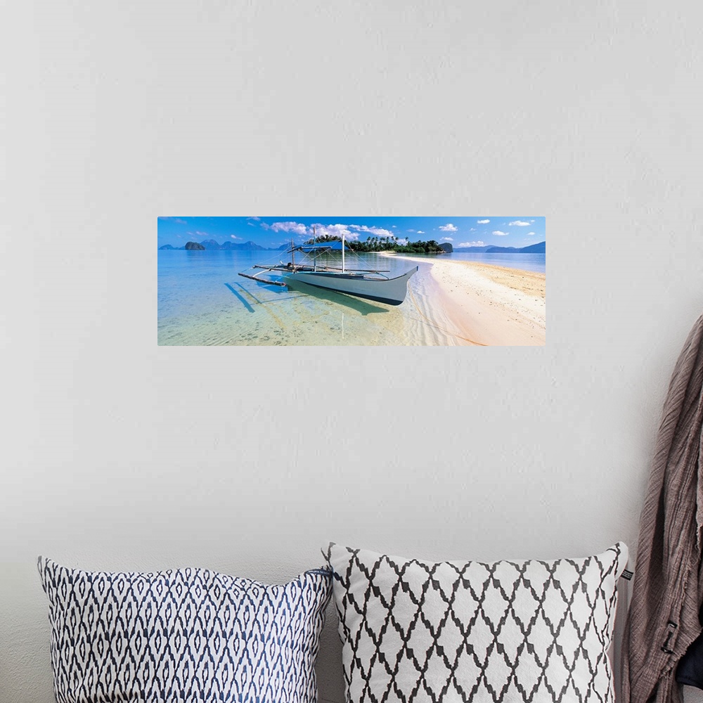A bohemian room featuring Panoramic photograph displays a fishing vessel as it sits docked on the sandy shores of a coastal...