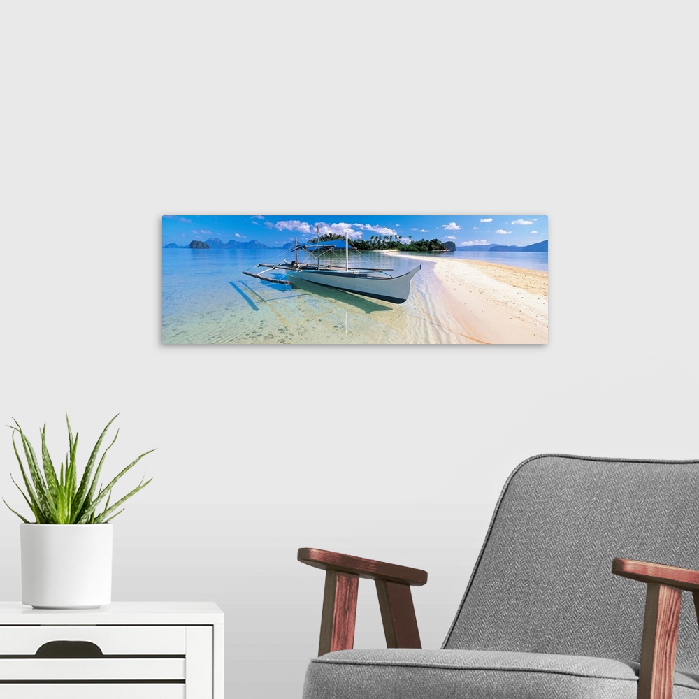 A modern room featuring Panoramic photograph displays a fishing vessel as it sits docked on the sandy shores of a coastal...