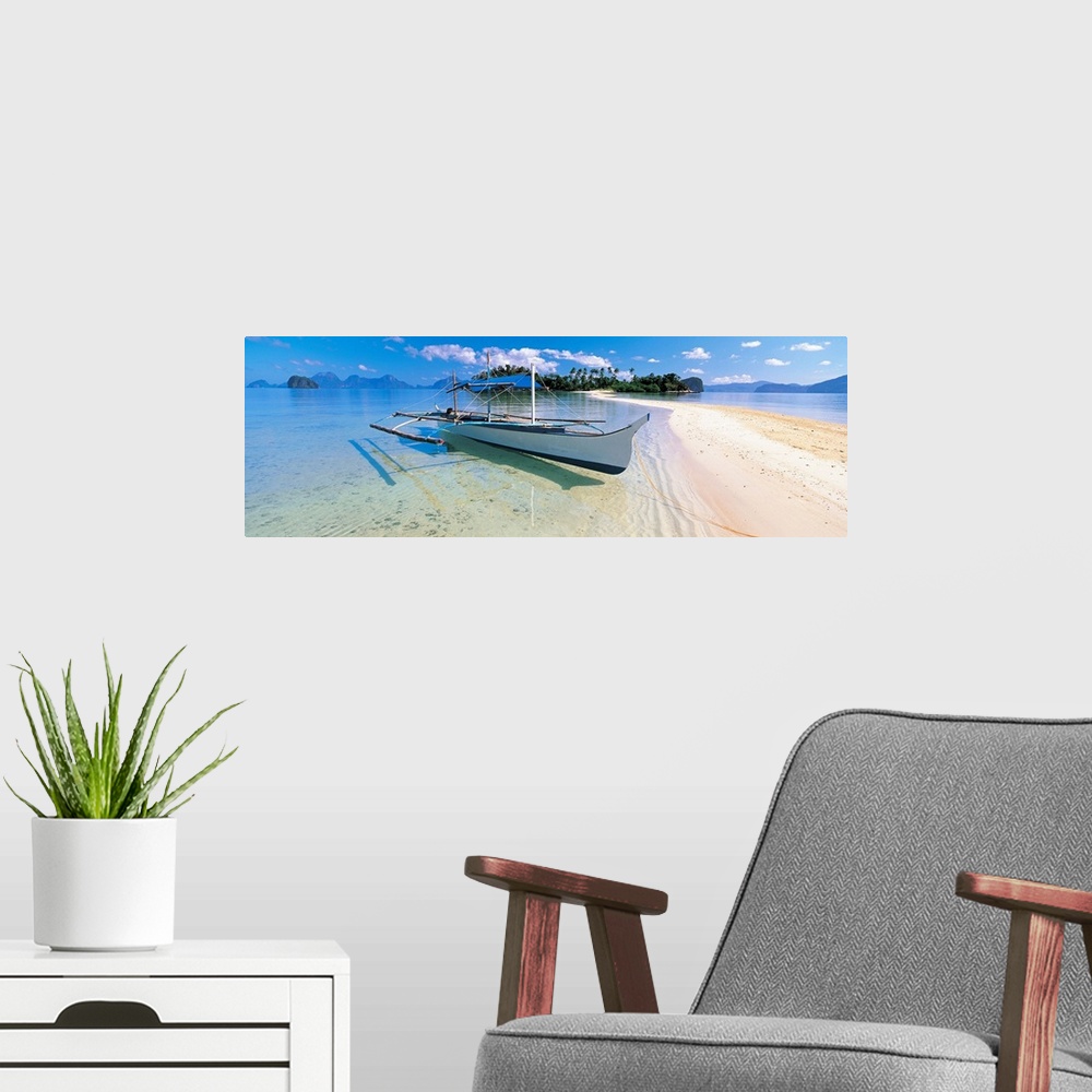 A modern room featuring Panoramic photograph displays a fishing vessel as it sits docked on the sandy shores of a coastal...