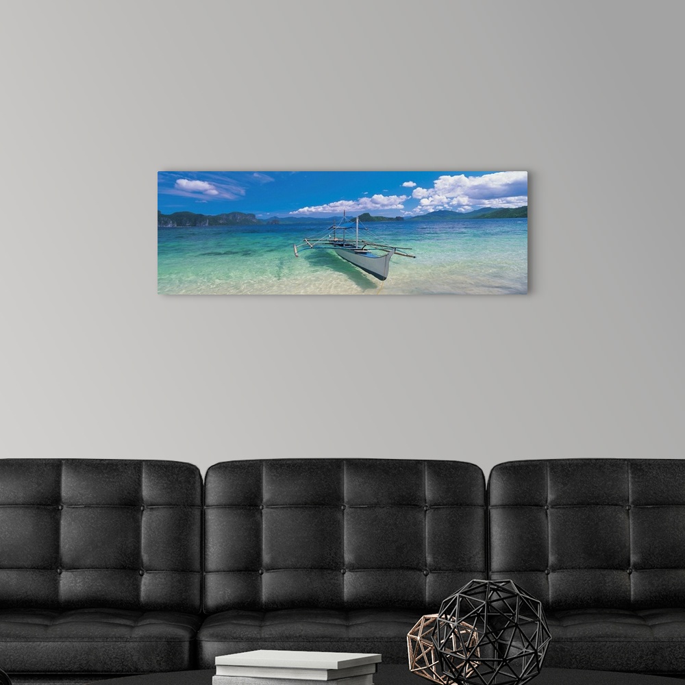 A modern room featuring Panoramic photograph of a canoe atop crystal clear waters with tree covered mountains and cliffs ...