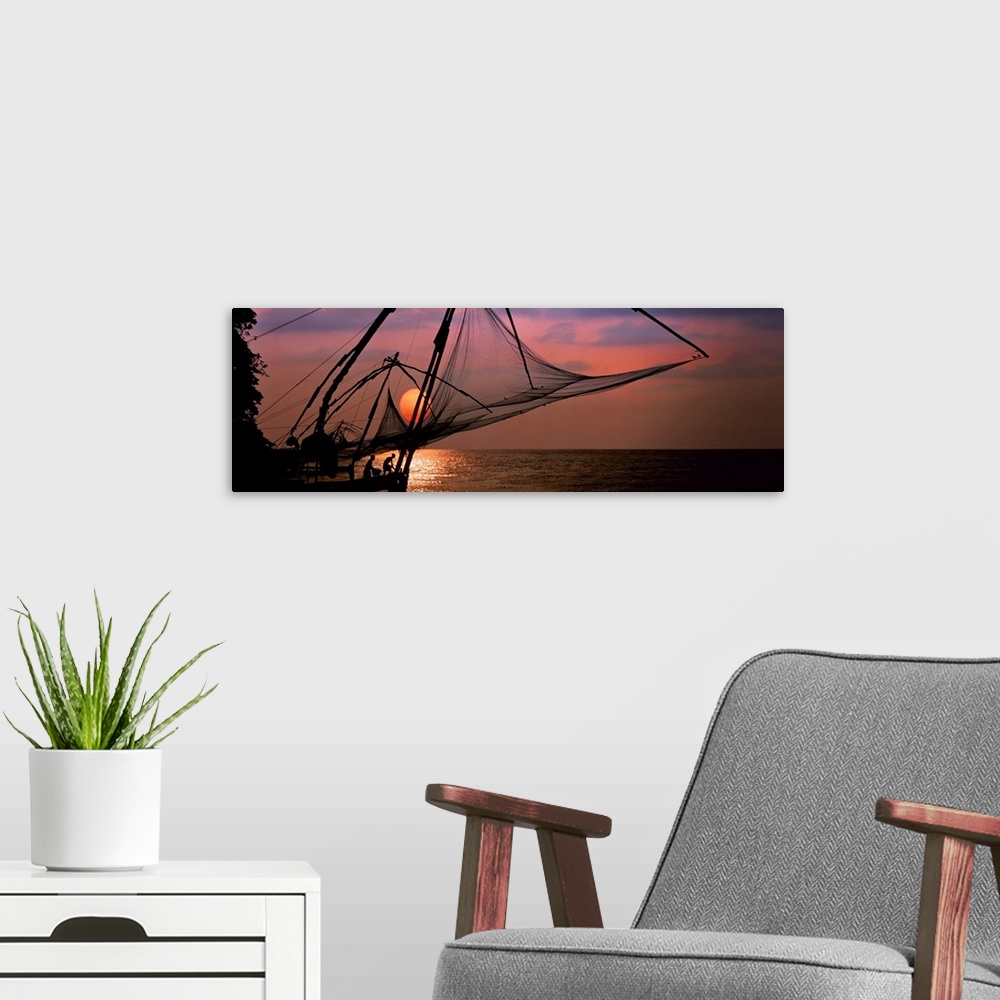 A modern room featuring Panoramic photo of fishing nets silhouetted against a big setting sun.