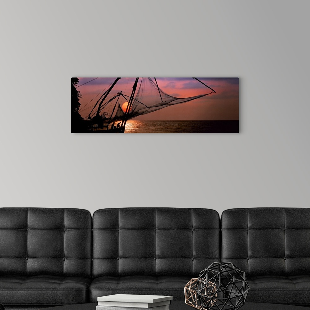 A modern room featuring Panoramic photo of fishing nets silhouetted against a big setting sun.