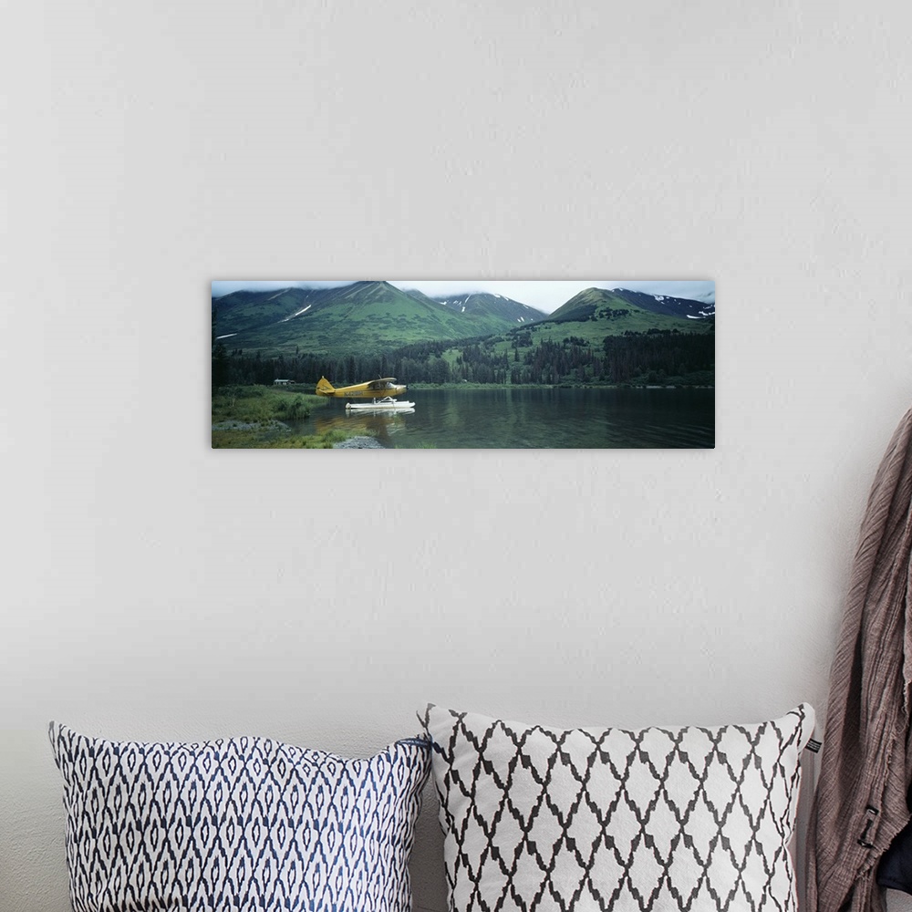 A bohemian room featuring Panoramic photograph of airplane on skis in lake with mountains in the distance.