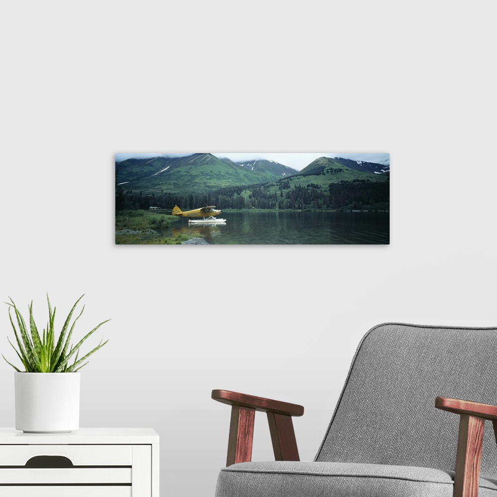 A modern room featuring Panoramic photograph of airplane on skis in lake with mountains in the distance.
