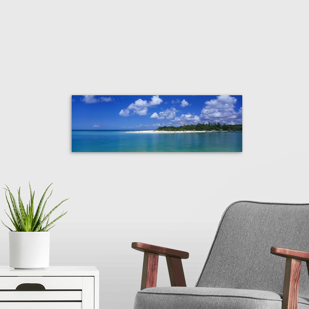 A modern room featuring Large panoramic photograph of a small beach off the coast in Florida with teal colored water surr...