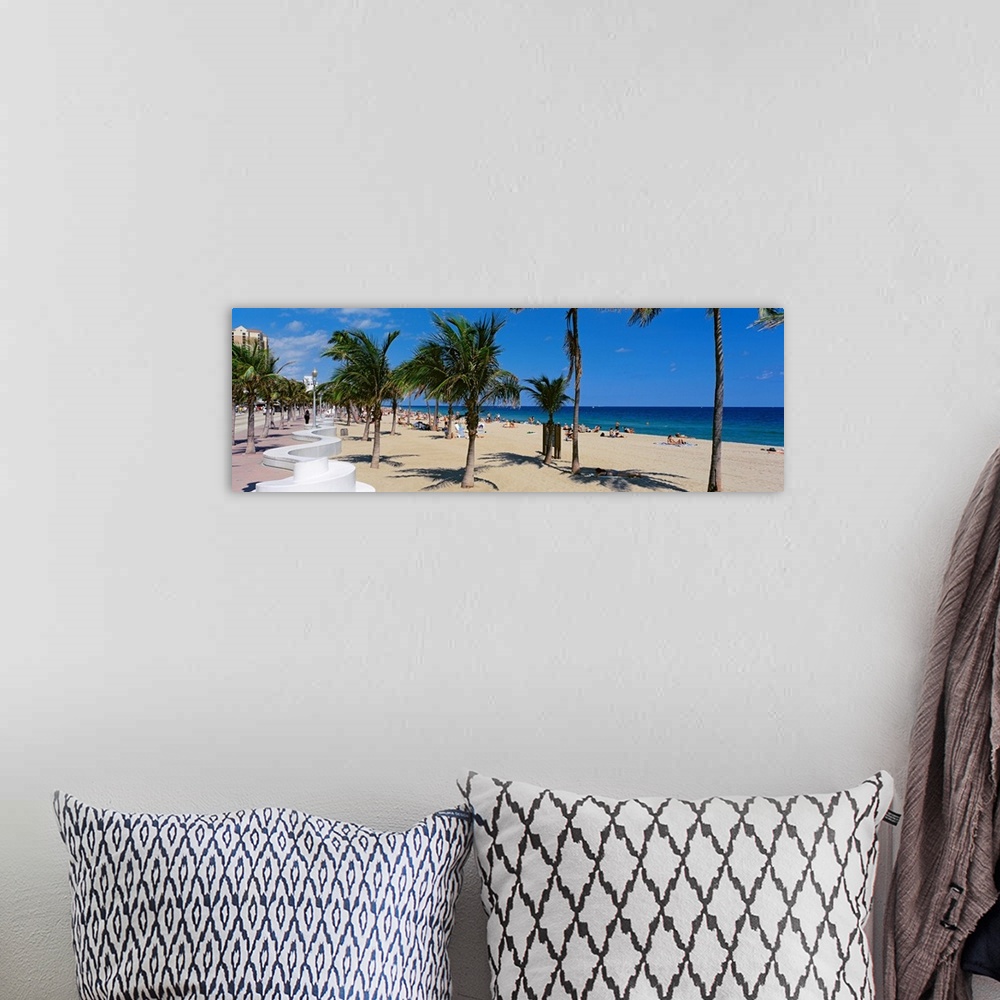 A bohemian room featuring Panoramic photograph showcases a lively beach scene scattered with people within Florida that has...