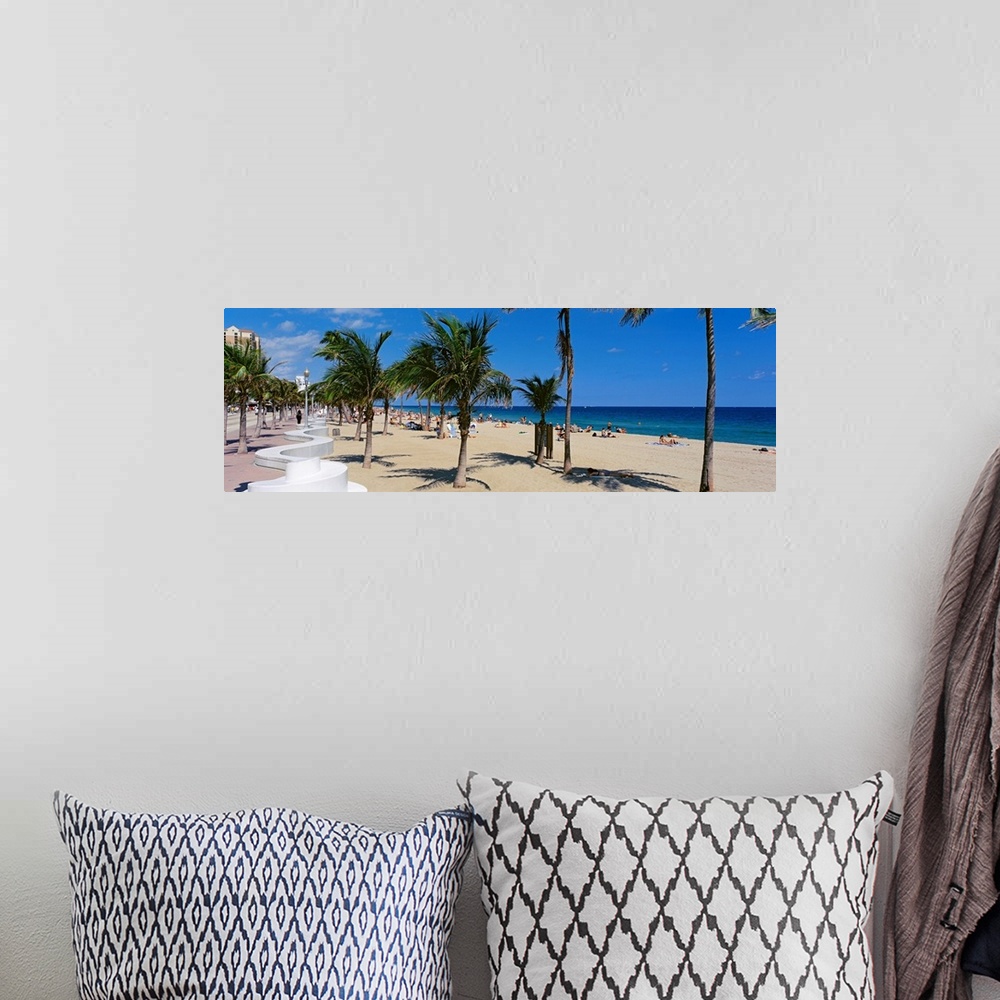 A bohemian room featuring Panoramic photograph showcases a lively beach scene scattered with people within Florida that has...