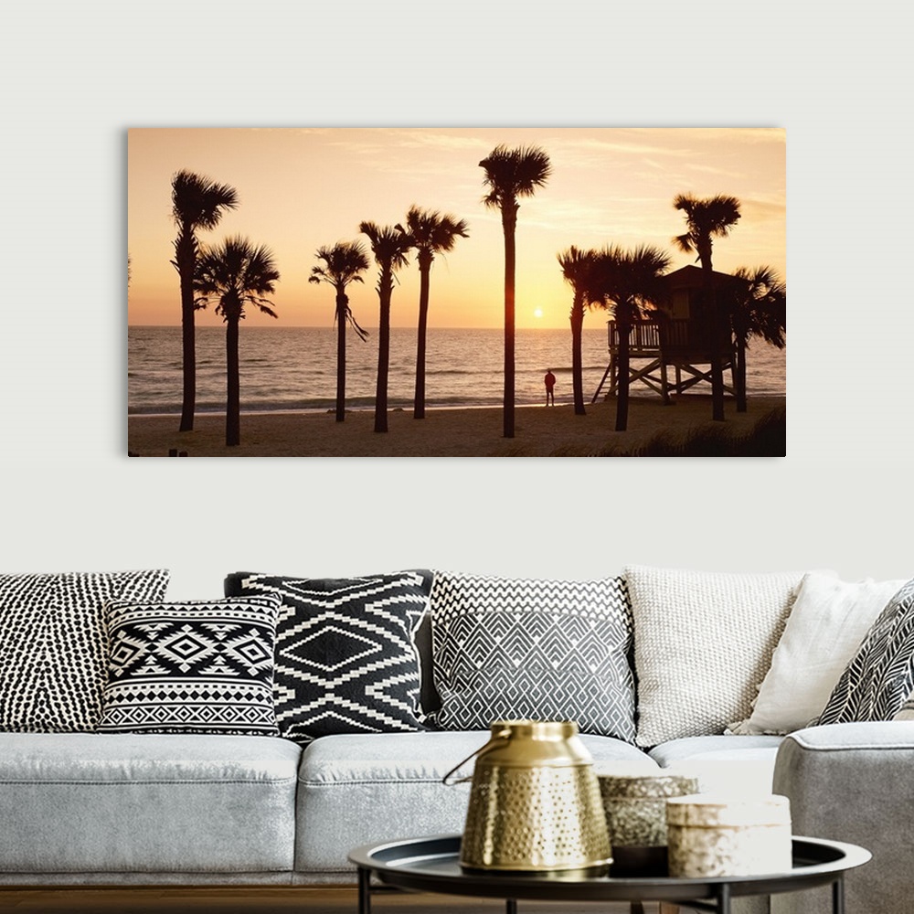 A bohemian room featuring Panoramic photo of palm trees lining a beach with a man standing on the shore looking out into th...
