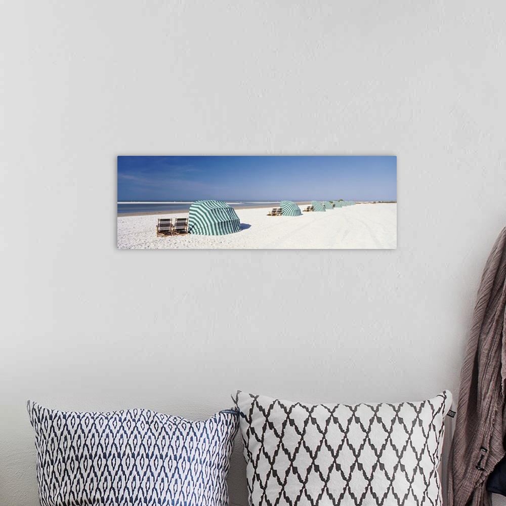 A bohemian room featuring Panoramic photograph of shoreline wish beach chairs and umbrellas under a clear sky.