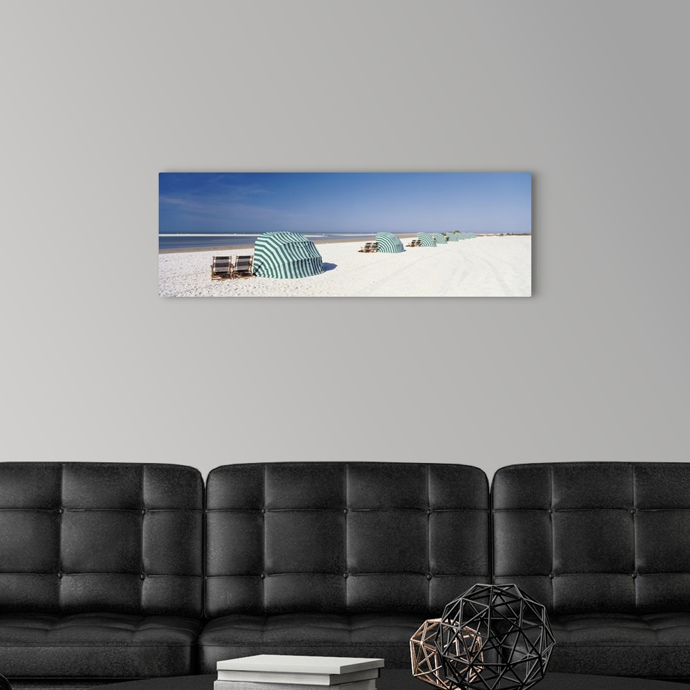 A modern room featuring Panoramic photograph of shoreline wish beach chairs and umbrellas under a clear sky.