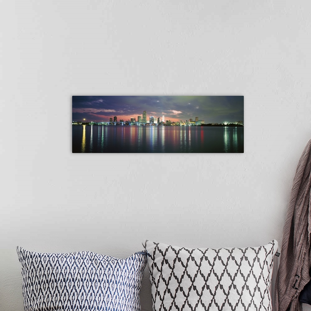 A bohemian room featuring This city scape photograph shows the city from a distance reflecting on the water on panoramic sh...