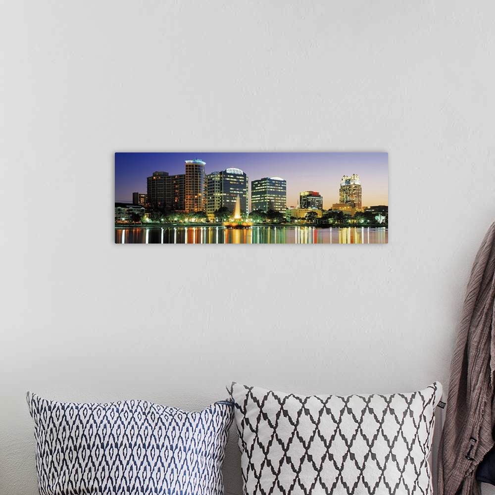 A bohemian room featuring The Orlando skyline is pictured in panoramic view with the buildings illuminated under an evening...