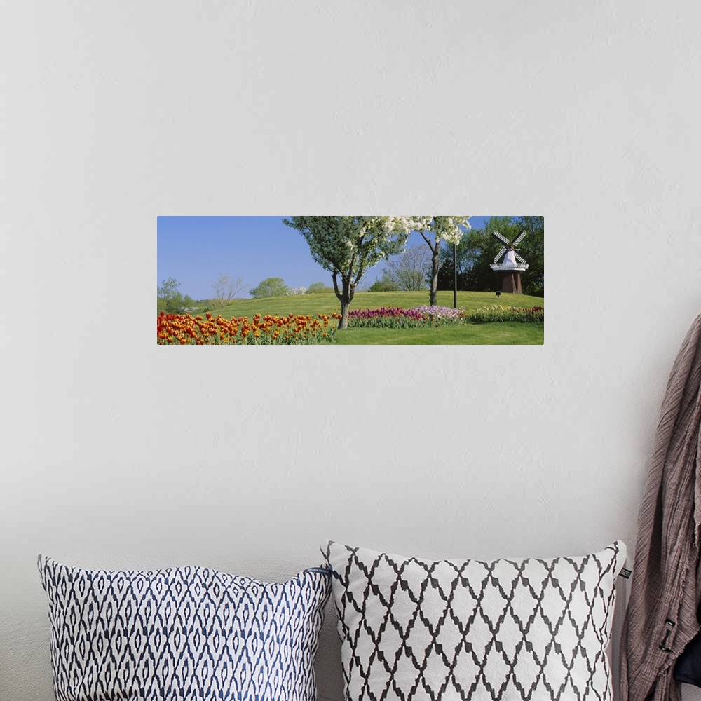 A bohemian room featuring Various colored tulips and flowering trees are pictured to the left of a small windmill.
