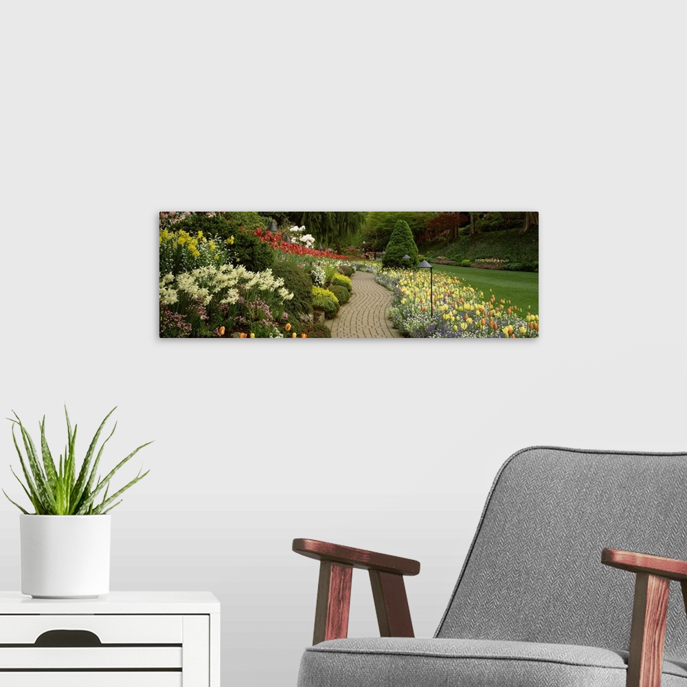 A modern room featuring Giant, landscape photograph of a brick path leading through vibrant flowers and shrubs, in Butcha...