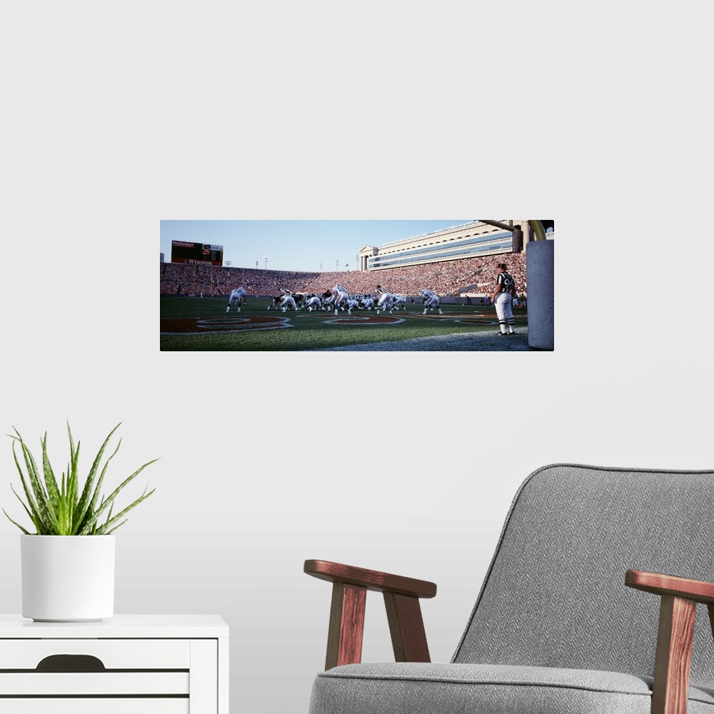 A modern room featuring Panoramic picture taken of the Chicago bears on the field at the scrimmage line with the stadium ...