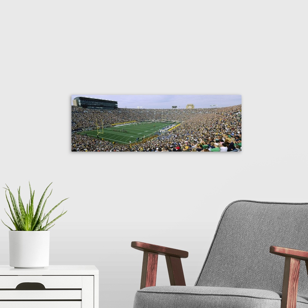 A modern room featuring Wide angle photograph of Notre Dame Stadium, full of fans during a football game, in South Bend, ...