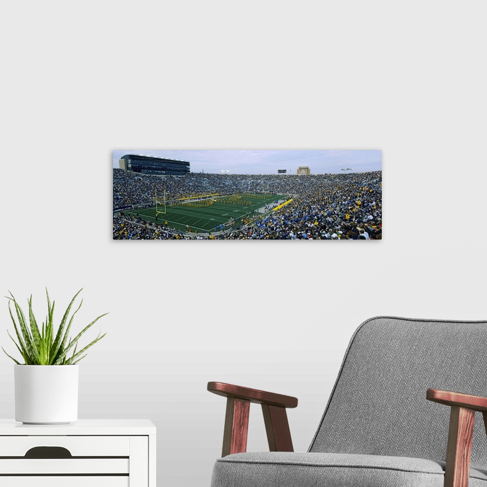 A modern room featuring A large panoramic picture taken inside a packed Notre Dame football stadium while the band is pla...