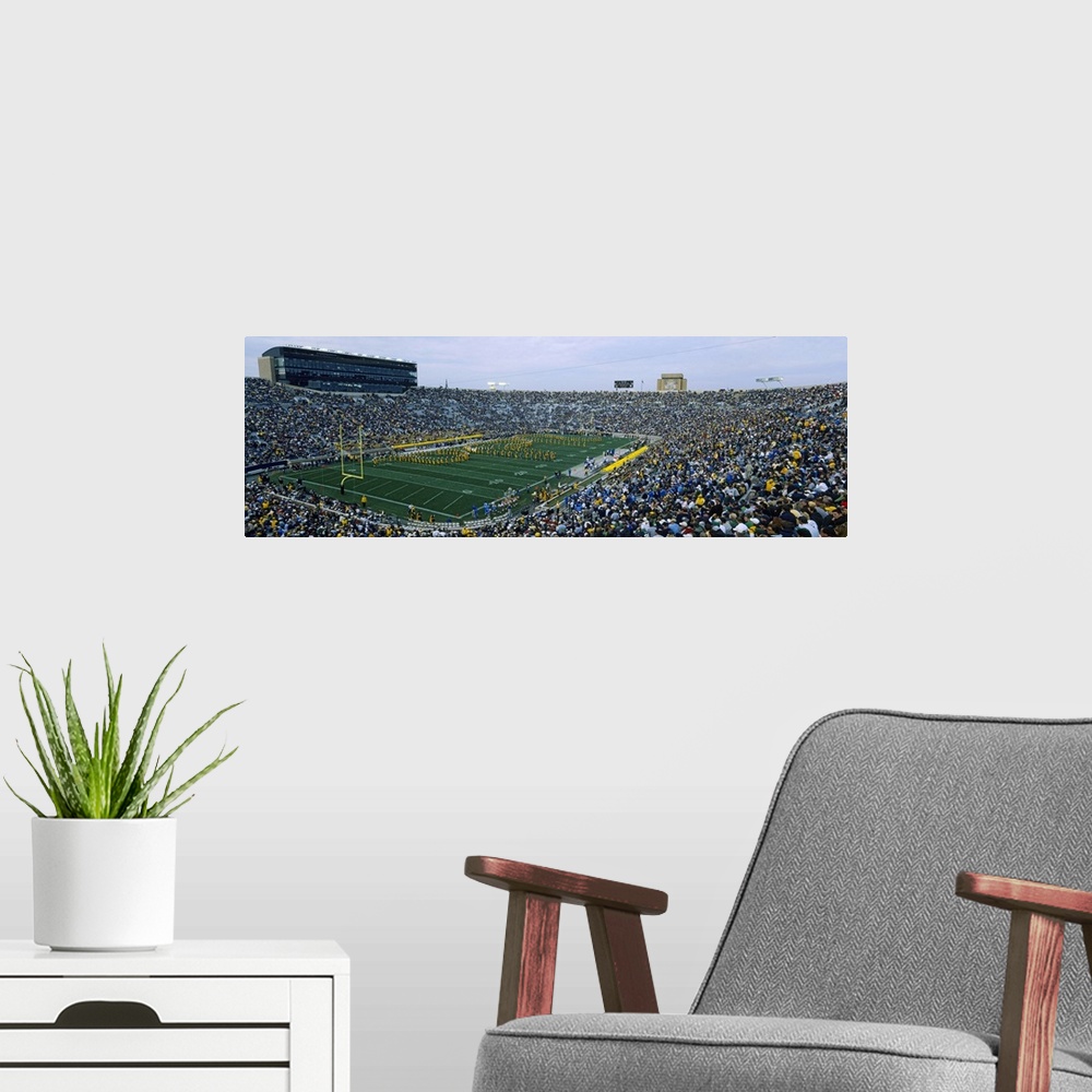 A modern room featuring A large panoramic picture taken inside a packed Notre Dame football stadium while the band is pla...