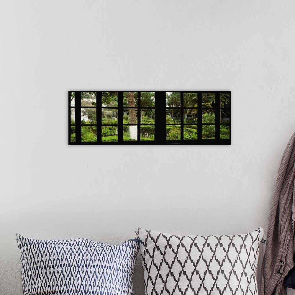 A bohemian room featuring Panoramic image looking out of a silhouetted window into a garden.