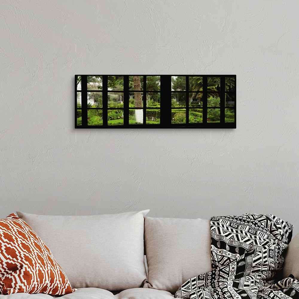 A bohemian room featuring Panoramic image looking out of a silhouetted window into a garden.