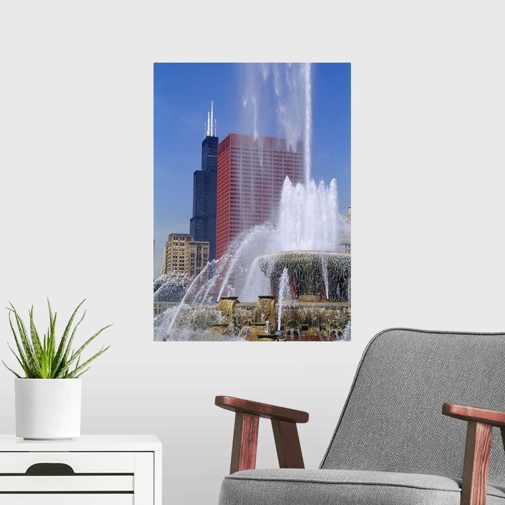 A modern room featuring A large fountain shoots water up high with a view of skyscrapers in Chicago shown in the background.
