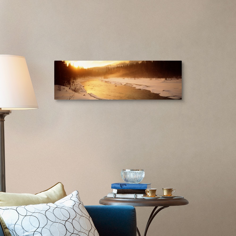 A traditional room featuring Panoramic image of a river running through a frozen landscape with fog coming off it and warm sun...
