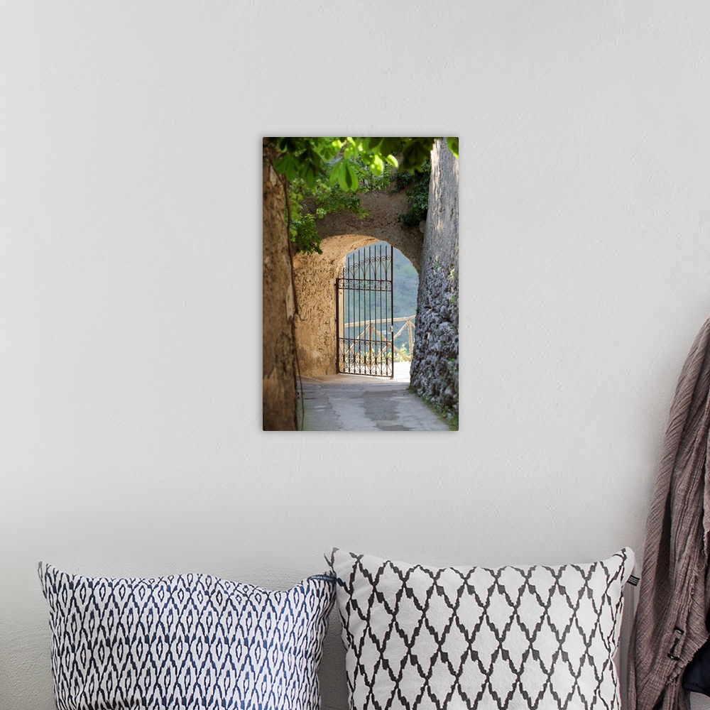 A bohemian room featuring A vertical photograph of a walkway lined with old masonry a green vines to an open iron wrought g...