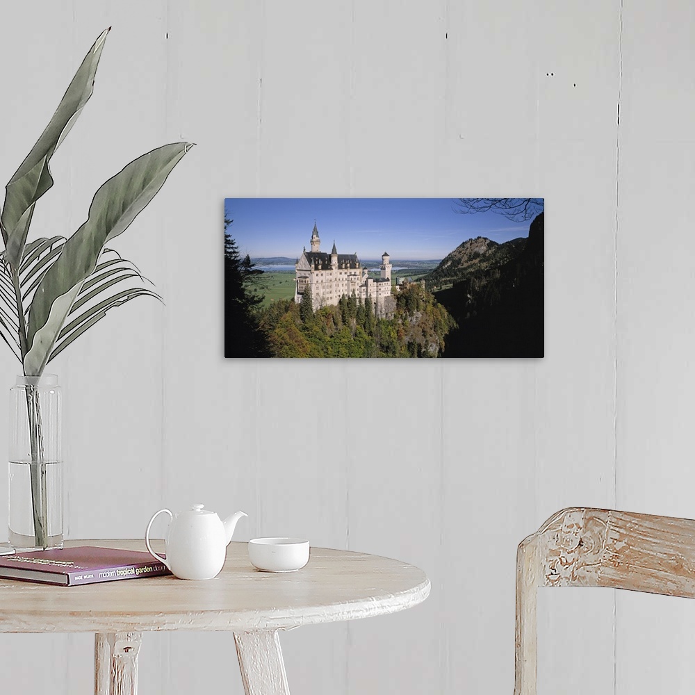 A farmhouse room featuring A landscape photograph of an elegant caste build on top of a steep, tree covered hill.