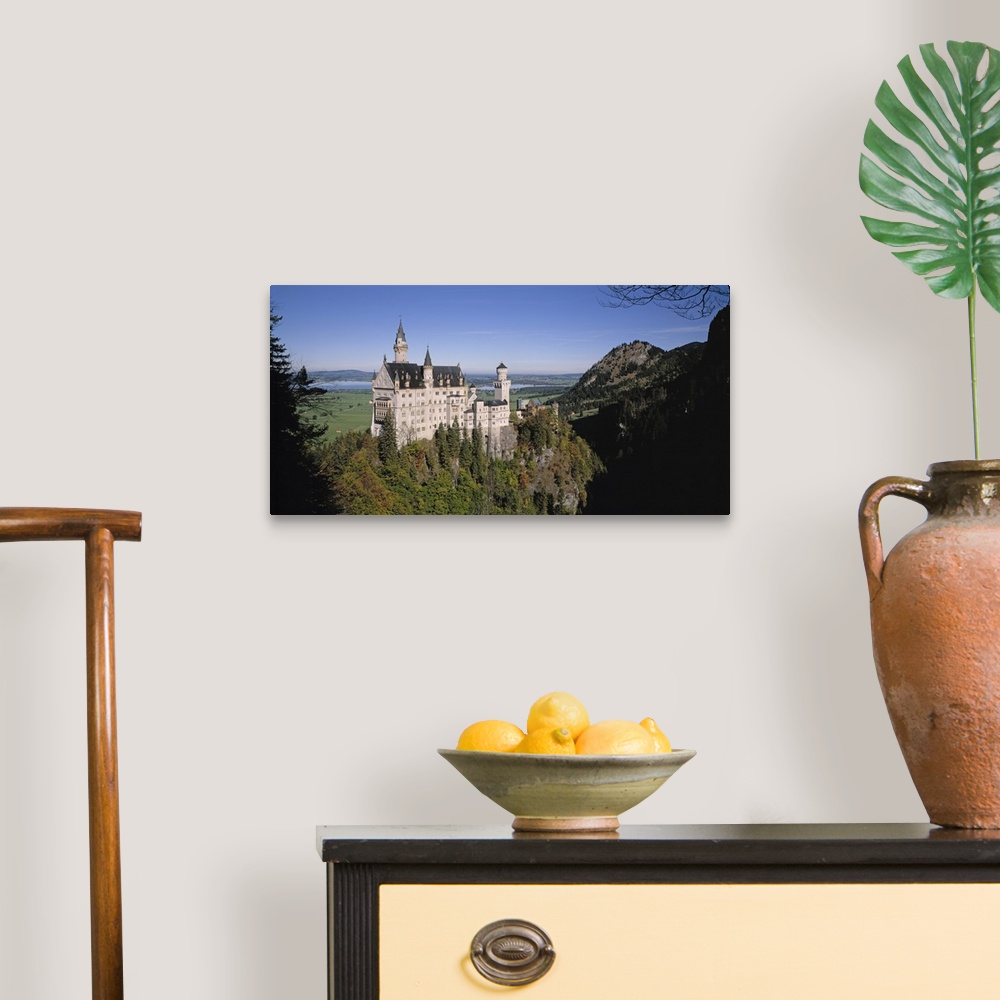 A traditional room featuring A landscape photograph of an elegant caste build on top of a steep, tree covered hill.