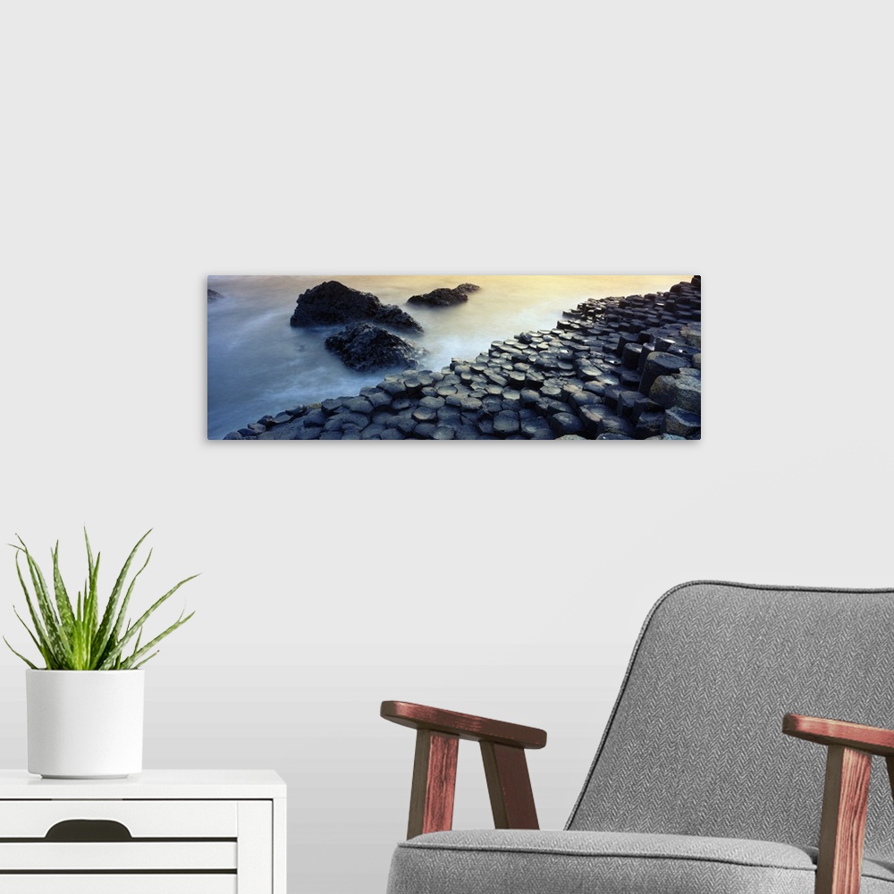 A modern room featuring Panoramic photograph of rocky shoreline with large stone formations rising from mist covered ocean.
