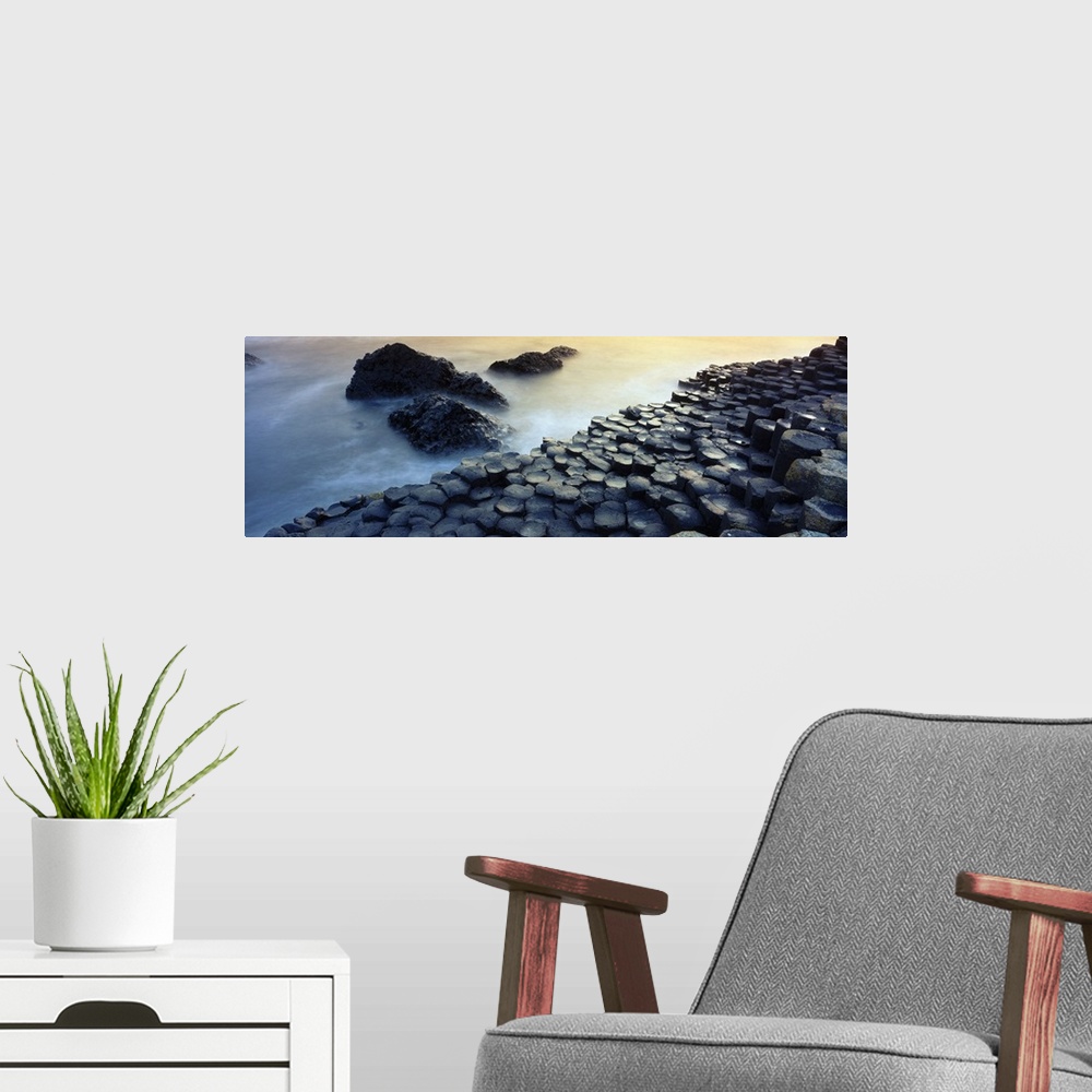 A modern room featuring Panoramic photograph of rocky shoreline with large stone formations rising from mist covered ocean.